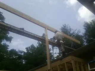 Carpenter setting a ridge beam over a new addition frame — Ice Dam Removal by Roofing Brothers in Winslow