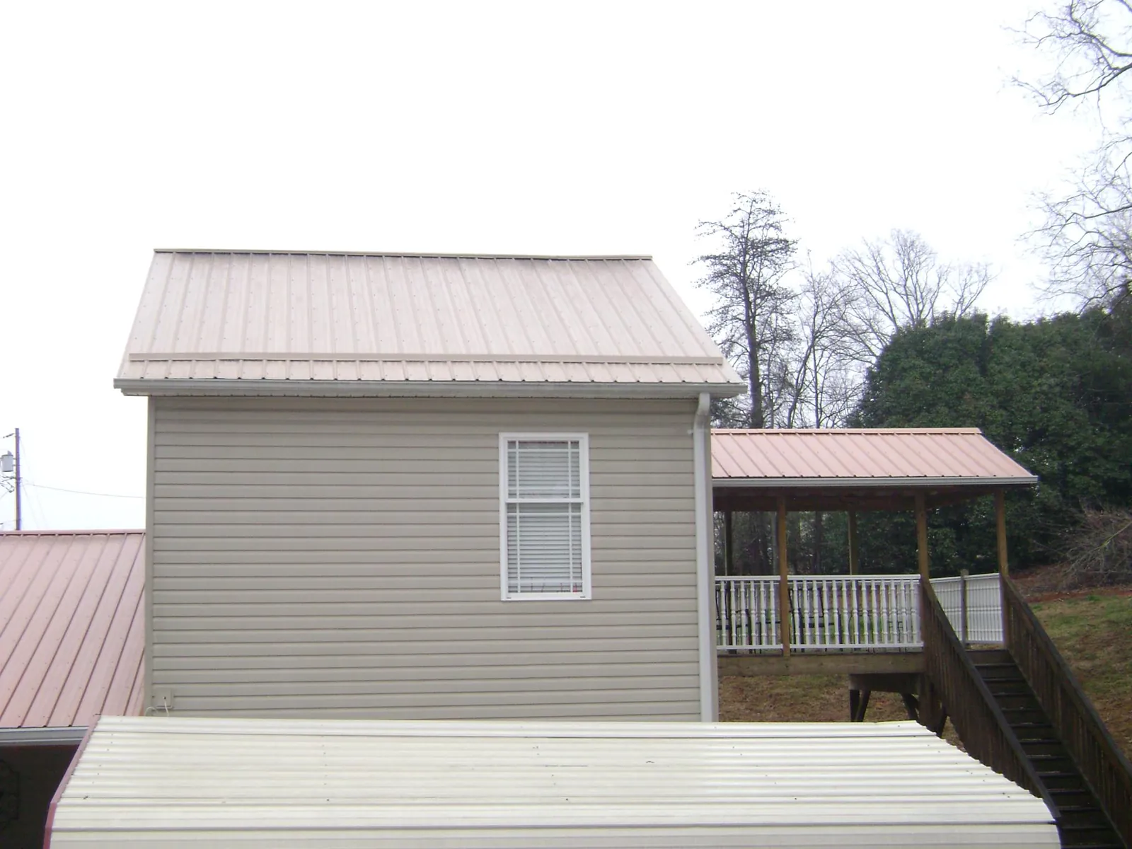 Tan metal roofs on a two story addition and attached porch, from a Roof Replacement job in Winslow